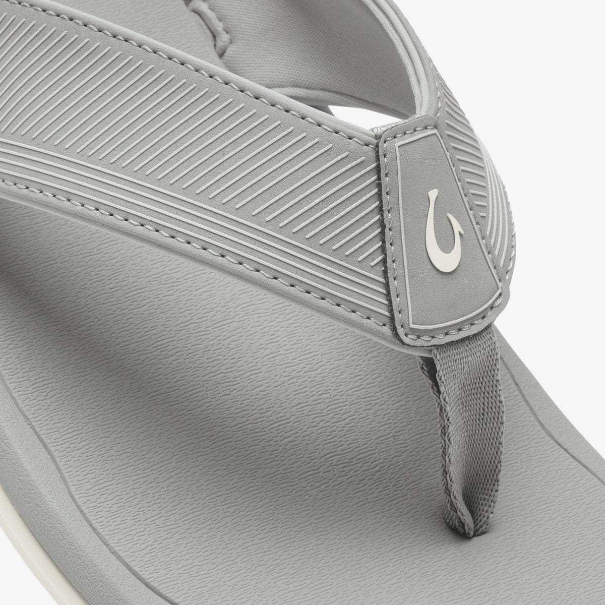 Light gray thong sandal with textured upper strap, white logo detail, and white sole.