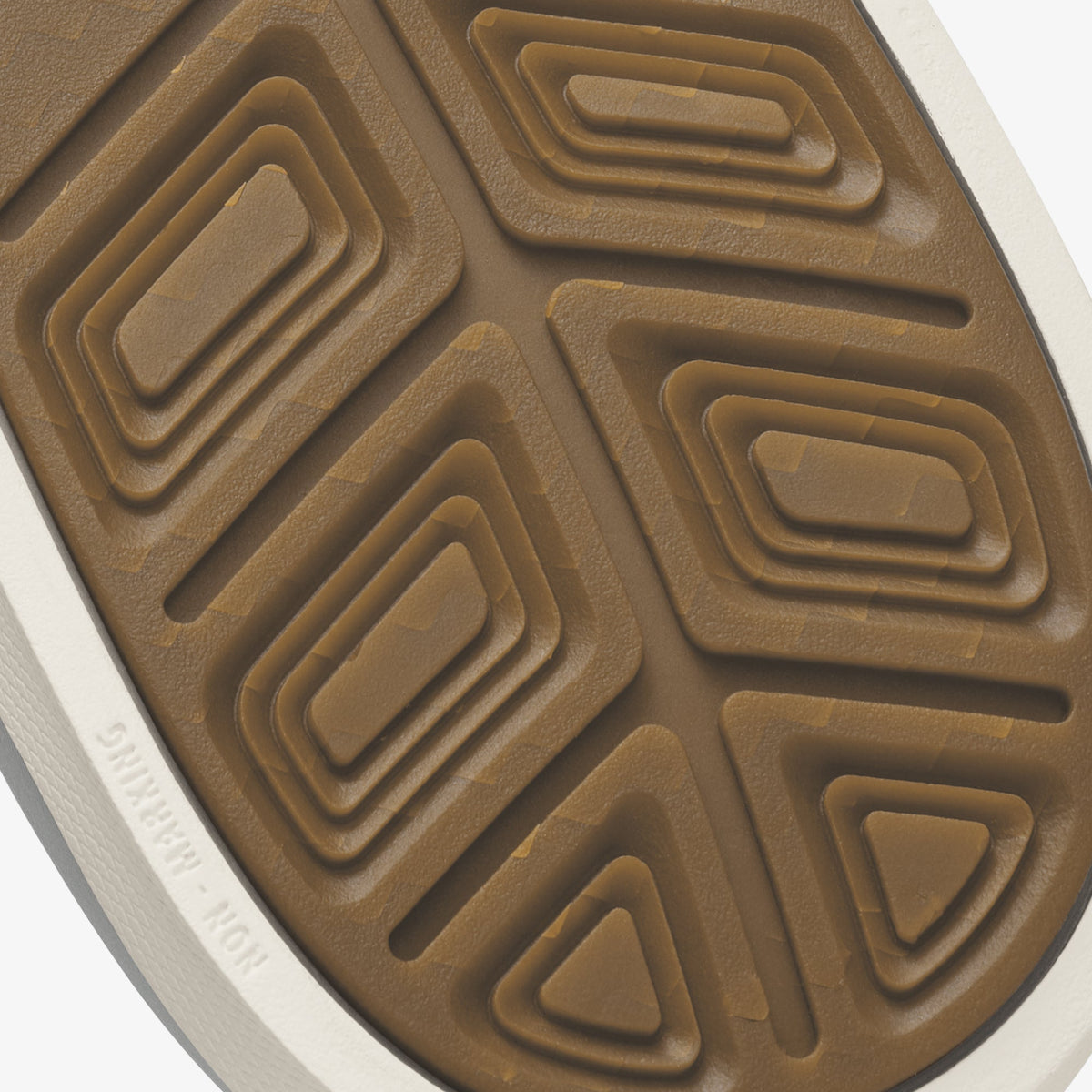 Tan sole with geometric tread pattern and white edge trim, viewed from below.