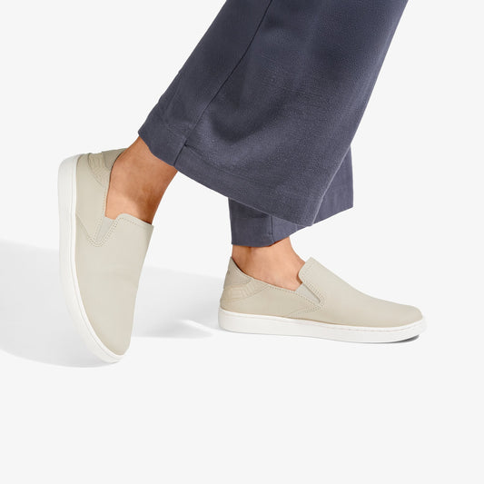 Cream leather slip-on shoes with white sole worn with dark blue pants.
